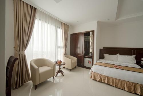 a bedroom with a bed and a chair and a window at Khách sạn Hoàng Thái in Sầm Sơn