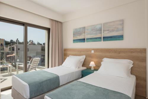 two beds in a hotel room with a balcony at Villa Kambos Platanias in Plataniás