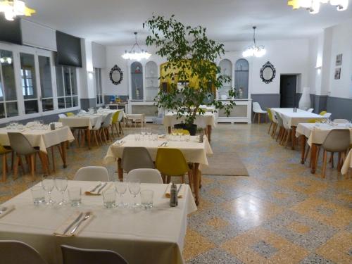 un comedor con mesas y sillas blancas en Hôtel Restaurant Le Commerce, en Auriol