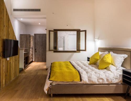 a bedroom with a bed with yellow pillows and a television at The Western Clouds in Deqing