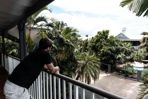 a man standing on a balcony looking at a garden at Motel Nomad in Cairns