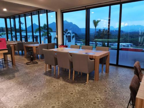 a dining room with tables and chairs and windows at Belong Jin The Dam Hotel And Resort in Ban Pha Saeng Lang