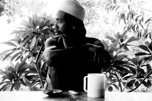 a woman sitting at a table with a cup of coffee at Merdeka House in Maluk
