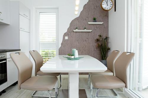 a white dining room with a white table and chairs at Apartments Mistral in Bol