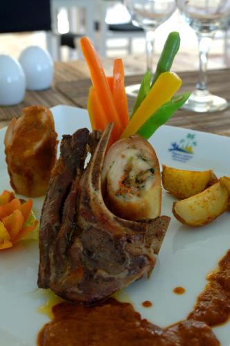 a plate of food with meat and vegetables on a table at Pigeon Island Beach Resort and Spa in Nilaveli