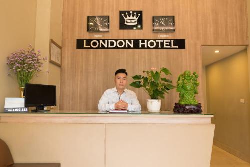 a woman sitting at a reception desk in a hotel at London Hotel in Ha Long