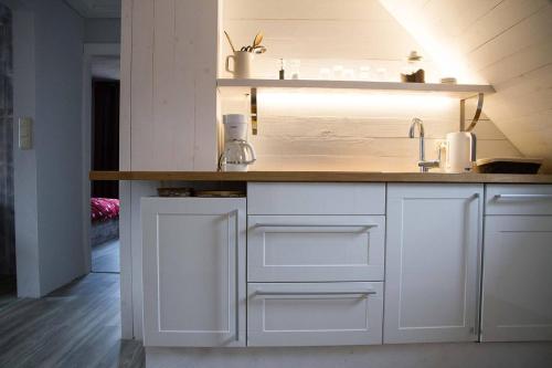 a kitchen with white cabinets and a wooden counter top at moevDECK in Heiligenhafen
