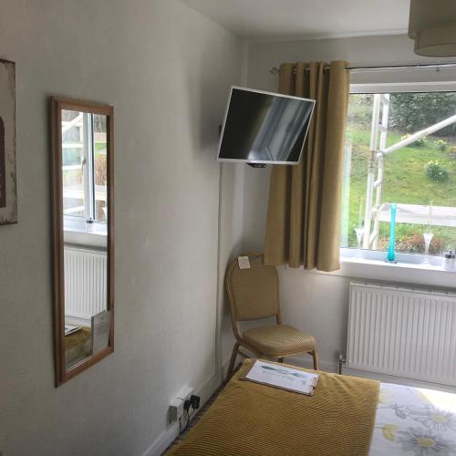 a room with a bed and a tv and a chair at glenardran house in Crianlarich