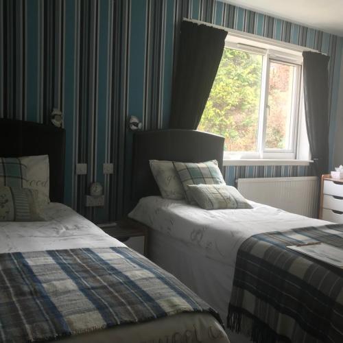 a bedroom with two beds and a window at glenardran house in Crianlarich