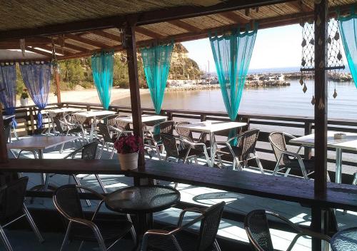 a restaurant with tables and chairs and a view of the water at Vokamvilia Apartment & Studio Close to the sea in Plános