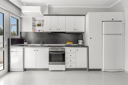 eine weiße Küche mit weißen Schränken und einem Kühlschrank in der Unterkunft 5- Luxury suite in the most central part of Rhodes! in Rhodos (Stadt)