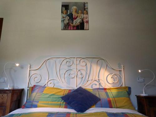 a bed with a white headboard with a picture on the wall at La Corte di Nonna Quercia in Cagli