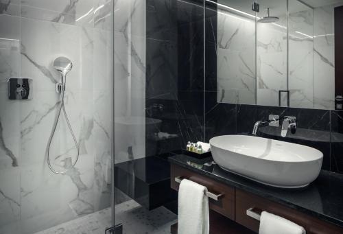 a bathroom with a sink, mirror, and bathtub at Hotel KINGS COURT in Prague
