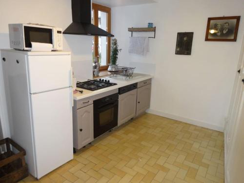 La cuisine est équipée d'un réfrigérateur blanc et d'un four micro-ondes. dans l'établissement appartement Landry, à Landry