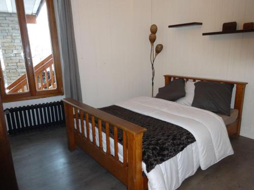 1 dormitorio con cama de madera y ventana en appartement Landry, en Landry