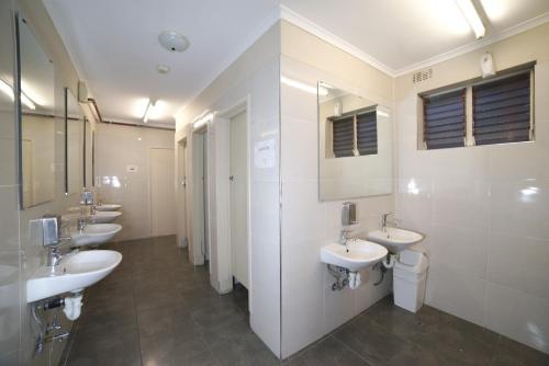 un bagno con quattro lavandini e una fila di specchi di City Centre Budget Hotel a Melbourne