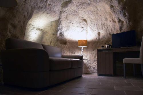 a living room with a couch and a television in a cave at 5 Elementi Sassi Matera in Matera