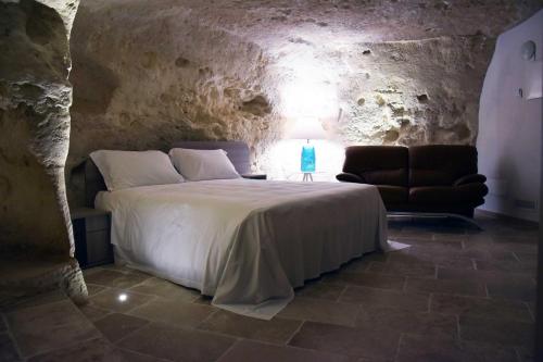 a bedroom with a bed and a chair in a cave at 5 Elementi Sassi Matera in Matera