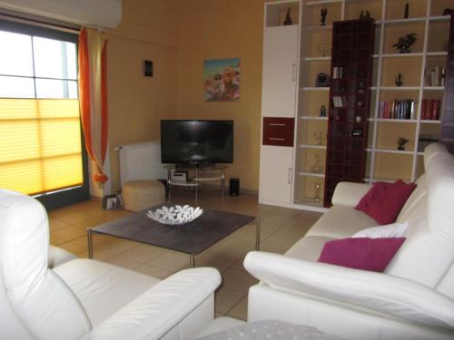 sala de estar con 2 sofás blancos y TV en Fewo Koje 22, en Ostseebad Karlshagen