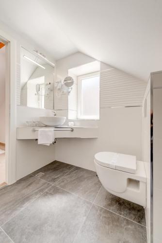 a white bathroom with a toilet and a sink at Apartments Villa Tudor in Hvar