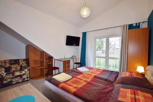 - une chambre avec un lit, un canapé et une fenêtre dans l'établissement Azalka Penzion, à Brno