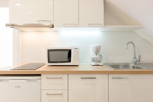a white kitchen with a microwave and a sink at Apartments Villa Tudor in Hvar