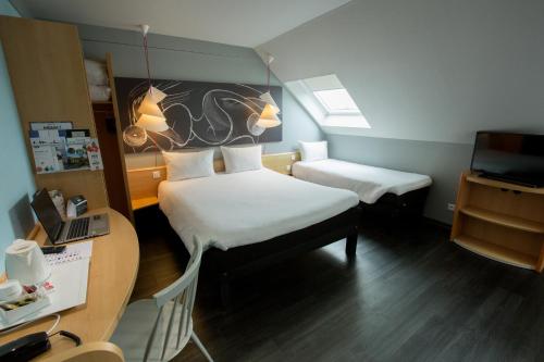 a small room with two beds and a desk at ibis Cherbourg La Glacerie in Cherbourg en Cotentin