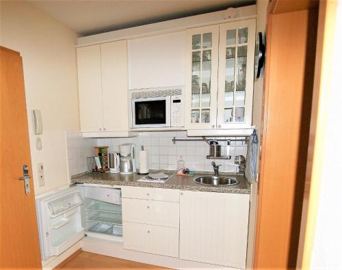 - une cuisine avec des placards blancs et un évier dans l'établissement Villa Seeblick 208: Lichtdurchflutet mit Ostseeblick!, à Sassnitz