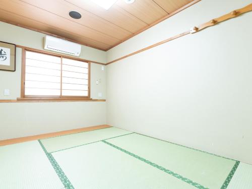 an empty room with white walls and a wooden ceiling at Sakura Ryokan Asakusa Iriya in Tokyo
