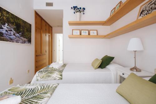 two beds in a room with white walls at El Refugio de San Luis con parking opcional in Seville