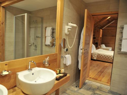 a bathroom with a sink and a shower and a bedroom at Bianca Resort & Spa in Kolašin