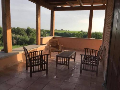 a porch with chairs and a table and a window at The Bell Tower Lodge in Palidoro