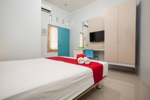 a bedroom with a large bed with two towels on it at RedDoorz @ Kartohardjo Madiun in Madiun