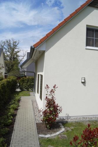 a white house with a sidewalk next to a yard at Ferienhaus Buche im Land Fleesensee in Göhren-Lebbin