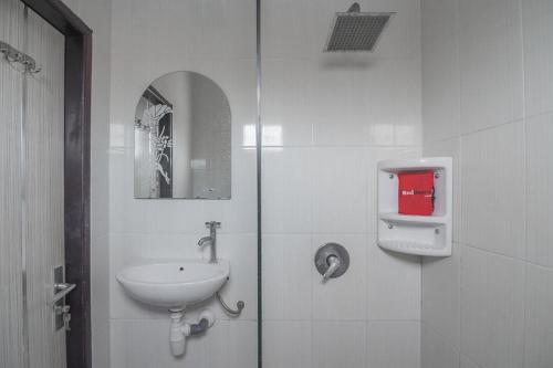 a white bathroom with a sink and a mirror at RedDoorz near E Walk Mall Balikpapan in Balikpapan