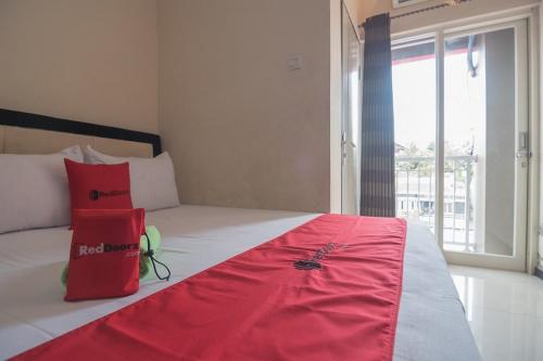a bedroom with a bed with red pillows and a window at RedDoorz near E Walk Mall Balikpapan in Balikpapan