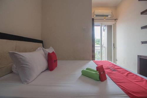 uma cama branca com almofadas vermelhas e verdes em RedDoorz near E Walk Mall Balikpapan em Balikpapan