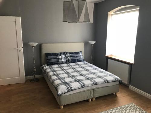 a bedroom with a bed with a plaid pillow and a window at Apartament 'Laura' Tykocin in Tykocin
