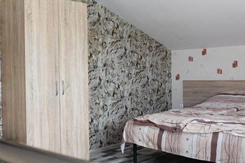 a bedroom with a bed and a stone wall at Guest House Valiland in Bŭlgarevo