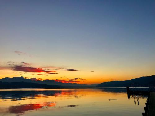 a sunset over a lake with mountains in the background at Villa Auguste in Pörtschach am Wörthersee