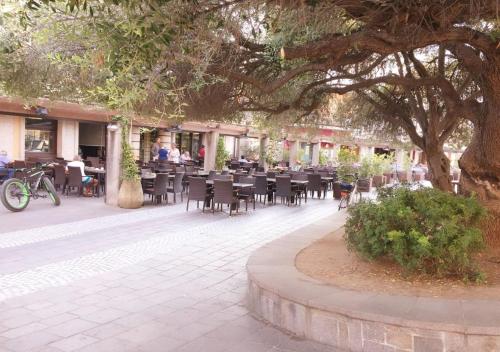 a patio with tables and chairs under a tree at Sophie Home - Comfort e Relax a pochi km da Nora in Pula