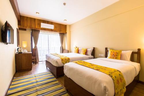 a hotel room with two beds and a television at Hotel Mala Pokhara in Pokhara