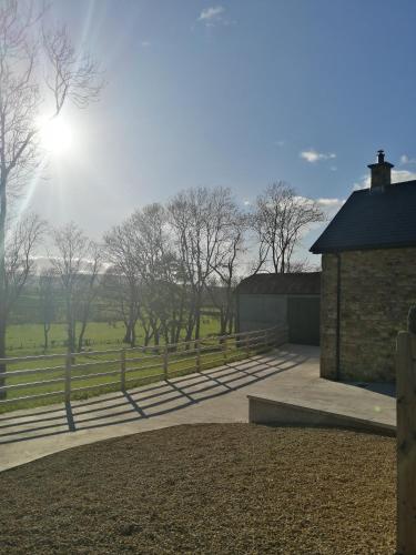 a building with a fence and trees in a field at Knockninny Barn at Upper Lough Erne, County Fermanagh in Enniskillen