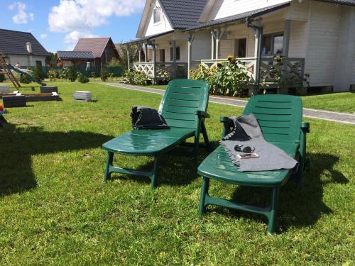 two green chairs sitting on the grass in a yard at Biale Domki Kopalino in Kopalino