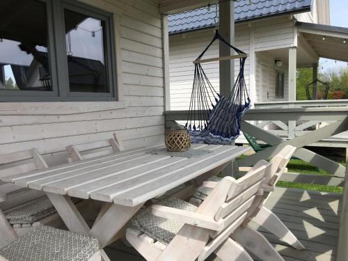 a porch with a swinging bench and two chairs at Biale Domki Kopalino in Kopalino