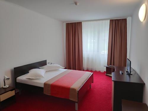 a hotel room with a bed with a red carpet at Hostel Caliman in Caciulata