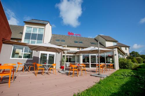 a wooden deck with chairs and tables and umbrellas at ibis Cherbourg La Glacerie in Cherbourg en Cotentin