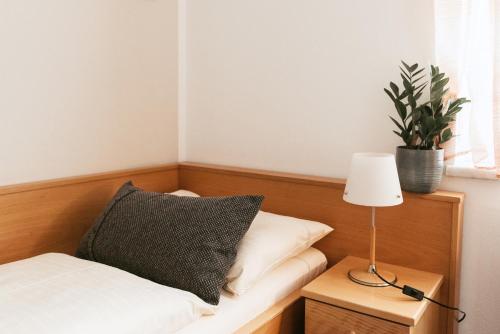 a bed with a pillow and a lamp on a night stand at Restaurant Gästehaus Feldkirchen in Feldkirchen bei Graz