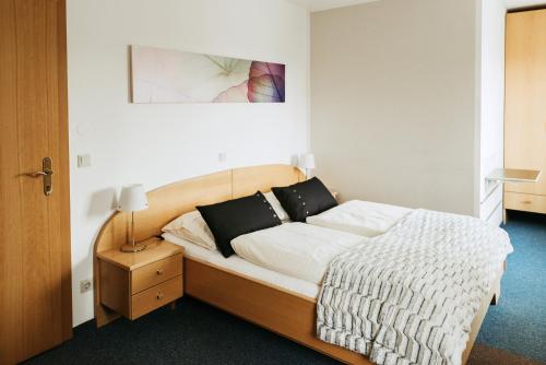 a bedroom with a bed with white sheets and black pillows at Restaurant Gästehaus Feldkirchen in Feldkirchen bei Graz