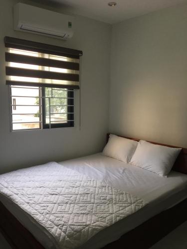 a bedroom with a white bed with a window at Huynh Gia in Da Nang